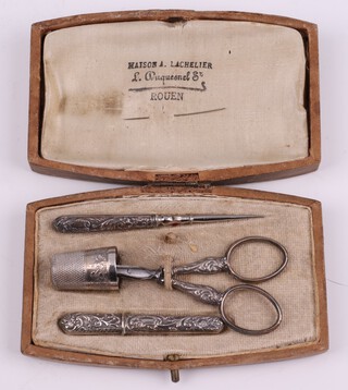  A Continental embossed metal 4 piece sewing set comprising bodkin, scissors, needle case and thimble 