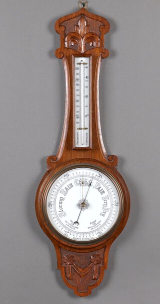An Edwardian aneroid barometer and thermometer with porcelain dial, contained in a carved oak wheel case 180cm h x 26cm w 