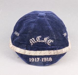 Two early 20th Century Rugby / Football caps in blue cloth with gilt braiding, one the crown with braided lettering "1918 M.C.F.C 1919" (possibly Manchester City Football Club), the brim lettered "1917 - 1918",  the other in blue cloth with gilt braiding, the crown with braided lettering "1918 1919", divided by a gilt logo of a Saltire beneath a Crescent, the brim lettered "1918-1918", both with label to interior "Aitken and Niven, 40 Queensbury St, Edinburgh"