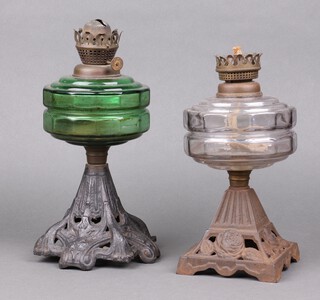 A Victorian green glass oil lamp reservoir raised on a pierced cast iron base 30cm and a clear glass oil lamp reservoir on a square base decorated roses 28cm 