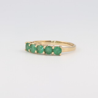 A 14ct yellow gold half eternity ring set 5 colour enhanced treated emeralds, size O, 1.7 grams