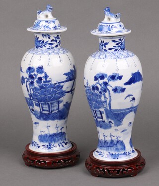 A pair of 1920's Chinese blue and white vases with covers, decorated landscapes, the base with 4 character mark 27cm 