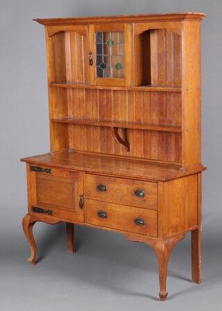 An Art Nouveau light oak dresser, the raised back with moulded cornice, fitted a cupboard enclosed by lead glazed panelled door flanked by recesses above a shelf and recess, the base fitted 2 drawers flanked by a cupboard with embossed metal hingers, raised on cabriole supports 192cm h x 137cm w x 50cm d 