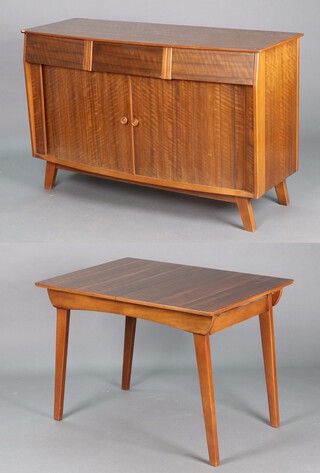 A mid-century rosewood finished dining suite comprising sideboard fitted 3 drawers above cupboard enclosed by tambour shutter on outswept supports 86cm h x 137cm w x 51cm d  and extending dining table on outswept supports 75cm h x 107cm x 76cm (3cm section of timber missing to the top) 