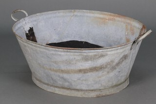 An oval galvanised metal twin handled bath 32cm h x 76cm w x 64cm d 