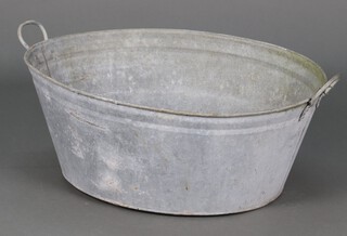 An oval galvanised metal twin handled bath 32cm h x 76cm w x 64cm d 