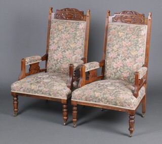 A pair of Art Nouveau carved walnut open arm chairs upholstered in floral patterned material, raised on turned supports 113cm h x 67cm w x 61cm d (frames loose, sun bleached in places)