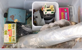 A collection of various model train rails, a transformer, etc in a plastic box, together with a collection of rails in a fruit box 