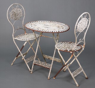 A pierced white painted metal Bistro style garden set comprising oval folding table 73cm h x 71cm w and 2 folding chairs  (rust in places)
