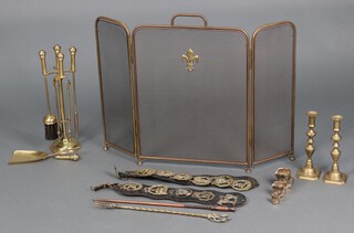 A gilt metal and mesh spark guard, a pair of 19th Century brass candlesticks, a fireside companion set and various martingales hung horse brasses 