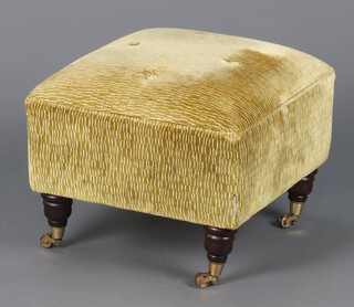 A footstool upholstered in green material on turned supports with brass caps and casters 39cm h x 51cm w x 51cm d 