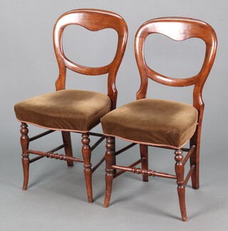 A pair of Victorian mahogany balloon back dining chairs with overstuffed seats, raised on turned supports 
