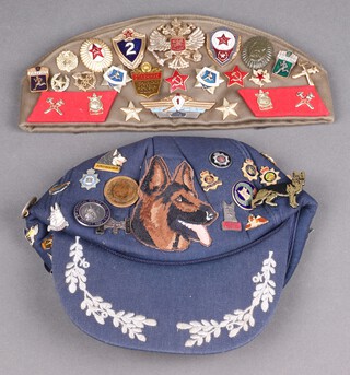 A Soviet Russian forage cap with numerous Soviet Russian badges together with a baseball cat with Alsatian badges 