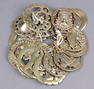 Fourteen reproduction brass horse brasses together with a pair of candlesticks in the form of cobras 