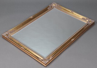 A rectangular bevelled plate mirror contained in a decorative gilt frame 106cm x 75cm 