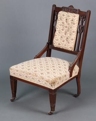 A Victorian carved and pierced mahogany nursing chair the  seat and back upholstered in floral material, raised on square tapered supports 90cm h  
