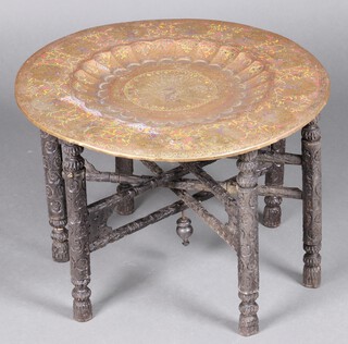 A circular Benares brass tray decorated a peacock raised on a carved and ebonised stand 43cm h x 59cm diam.