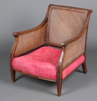 A 1920's beech framed Georgian style double cane bergere armchair, the arms carved rams heads, raised on square tapered supports 79cm h x 61cm w 