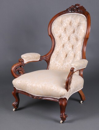 A Victorian carved and pierced walnut show frame armchair, the seat of serpentine outline upholstered in cream and floral buttoned material, raised on cabriole supports 104cm h 