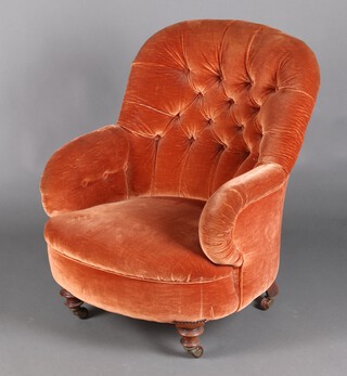 A Victorian armchair upholstered in orange buttoned material, raised on turned supports with ceramic casters 87cm h x 71cm w 