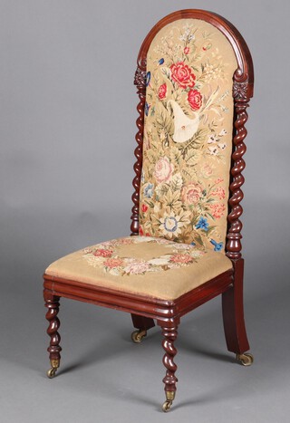 A Victorian mahogany show frame nursing chair, the seat and back upholstered in floral Berlin wool work with spiral turned columns to the sides, raised on spiral turned supports, brass caps and casters  104cm h x 46cm w x 40cm d 