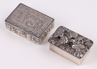 A rectangular silver pill box with cast hinged lid and floral decoration, London 1979, makers mark D E, 4.5cm together with a 925 embossed silver pill box with parcel gilt interior, gross weight 38 grams  