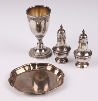 A silver waiter with bracketed border, Birmingham 1973, 8cm, 2 miniature silver pepperettes (charging to bases) Birmingham 1911 6cm, gross weight 59 grams and an embossed kiddish cup 8cm (some dents)
