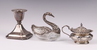 An oval embossed silver mustard pot with hinged lid and blue glass liner (marks rubbed) 37 grams, an Art Deco silver candlestick 7cm (dented, marks rubbed) and a German cut glass and silver salt in the form of a swan 7cm 