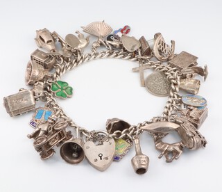 A silver curb link charm bracelet hung 29 numerous charms, 84.8 grams gross 
