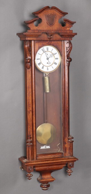 A Victorian regulator style wall clock with 16cm circular enamelled dial, Roman numerals, subsidiary second hand, complete with pendulum, weight and key, contained in a carved oak case 124cm h
