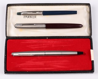A Parker fountain pen in a brushed stainless steel case, a 51 fountain pen in a red case and a Parker pen in a blue case 
