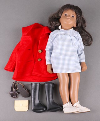 A Trendon Sasha Brunette doll, dressed in a gingham blue and white dress with white socks and shoes, together with and additional red coat, long black boots, black sandals and clutch bag