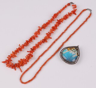 A silver mounted heart shaped pendant set butterfly wings 4cm together with 2 coral necklaces 41cm and 42cm 