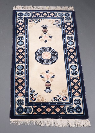 A 1930's blue and white ground Chinese rug with central medallion decorated urns 139cm x 70cm 