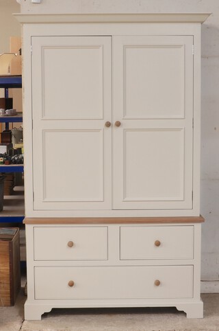 Neptune, a cream painted and oak press cabinet, the upper section with moulded cornice and fitted shelves  enclosed by a pair of panelled doors, the base fitted two short drawers above two long drawers 210h x 133w x 56d