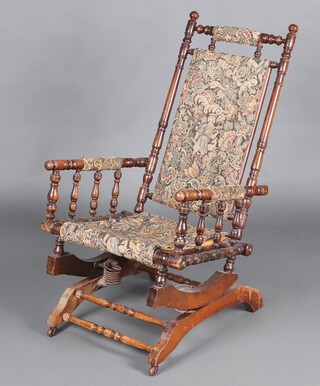 A 19th Century American turned beech rocking chair upholstered in tapestry material 103cm h 