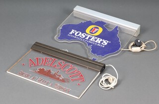 An Adelscott Biere au Malt a whisky rectangular plastic illuminated sign 36cm h x 56cm w together with a Fosters Beer sign 54cm h x 56cm w