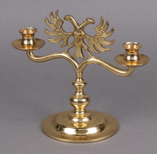 A brass twin light candelabrum surmounted by a double headed eagle 22cm h x 26cm w