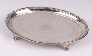 A George IV oval silver teapot stand with engraved decoration and bead work border, raised on panel supports, London 1824 by Thomas Pratt and Arthur Humphries 17cm, 143 grams 