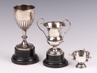 A silver goblet shaped trophy with demi-reeded decoration, inscribed, Birmingham 1928, a silver twin handled trophy cup Birmingham 1945, marks rubbed and a 3 handled silver trophy cup, marks rubbed, 174 grams 