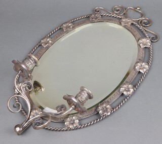 An oval bevelled plate wall mirror contained in a pierced and engraved silver plated frame, the base with 2 sconces 48cm h x 30cm w 