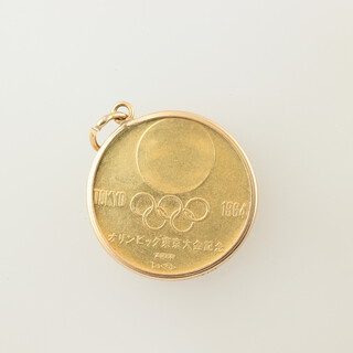 An 18ct gold 1964 Tokyo Olympics medallion in 14k mount depicting runners, 8.1 grams 