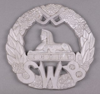 A cast aluminium wall plaque in the form of a South Welsh Borderers cap badge 23cm