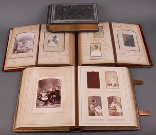 A Victorian plush bound photograph album containing 18 portrait photographs, a Victorian black bound photograph album with gilt mounts containing 54 portrait photographs, and an empty Victorian photograph album contained in a deeply carved Eastern hardwood cover (missing sections of veneer) 