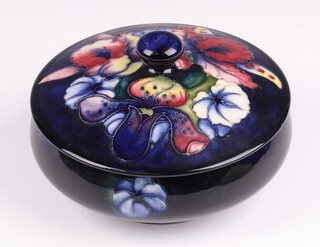 A Moorcroft Iris pattern powder bowl and cover on a blue ground, 7cm x 13cm, base impressed Moorcroft Made in England 