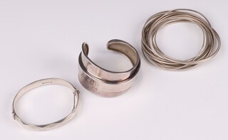 A silver bangle (clasp damaged), an unmarked silver cuff bangle together with 18 interlinked unmarked silver bangles, 169 grams 
