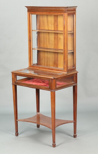 An Edwardian inlaid mahogany display cabinet, the upper section with moulded cornice, fitted shelves enclosed by a glazed panelled door, the base incorporating a bijouterie table, raised on square tapered supports with undertier, ending in spade feet 142cm h x 57cm w x 42cm d 