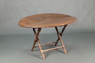 A 19th Century circular beech folding coaching table, raised on turned supports 64cm x 101cm 