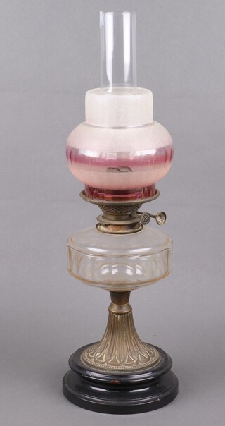 A Victorian faceted glass oil lamp reservoir raised on an embossed metal foot with circular ceramic base, complete with glass chimney and associated opaque glass shade 56cm h 