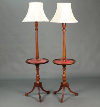 A pair of turned and reeded beech standard lamps, each incorporating a wine table with red inset surfaces, raised on a pillar and tripod bases 134cm h x 40cm diam.  